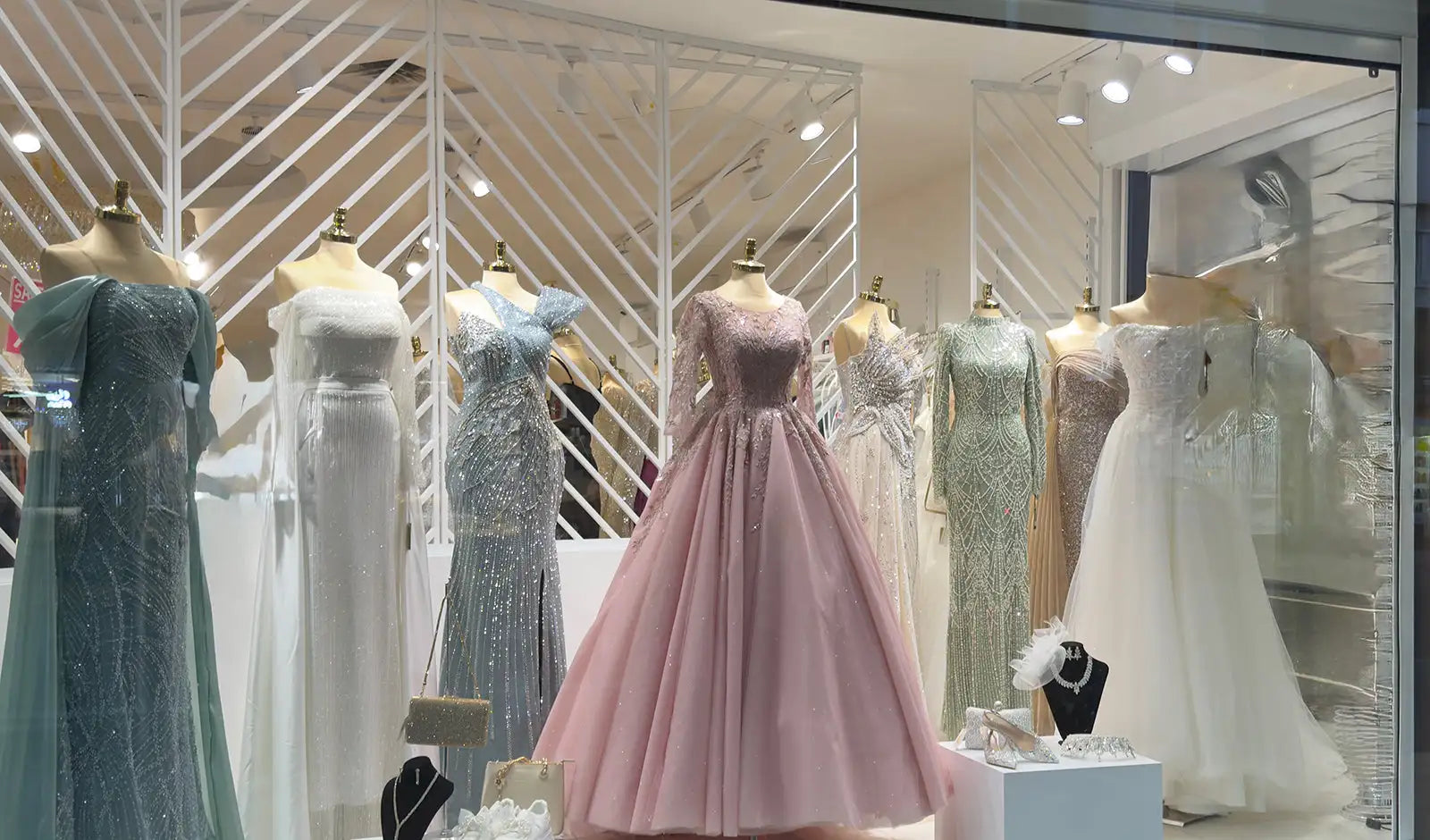 Ein fließendes rosa Satin-Kleid mit engem Oberteil und voluminösem Rock, ausgestellt auf einer Schaufensterpuppe in einem Schaufenster einer Boutique.