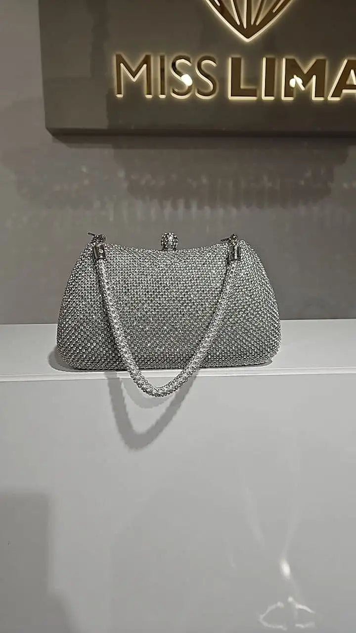 Eine funkelnde silberne Clutch-Tasche mit einer texturierten Oberfläche, verziert mit Kristallen, und passendem Kettenriemen.