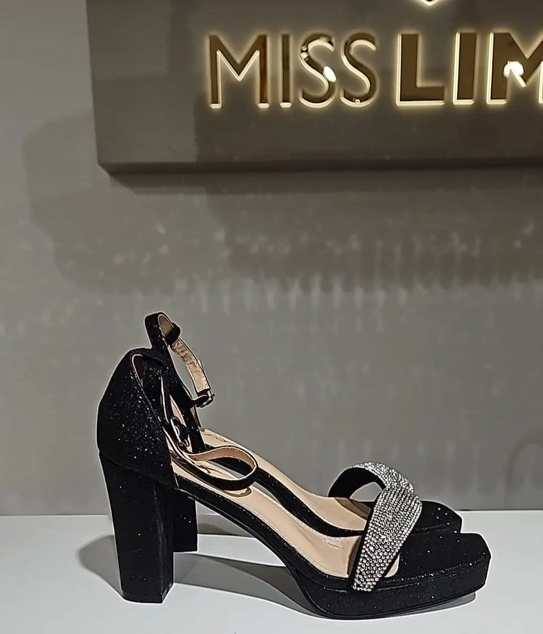 Schwarze glitzernde Plattform-Sandale mit einem silbernen Strapazierband, das mit Strasssteinen verziert ist.