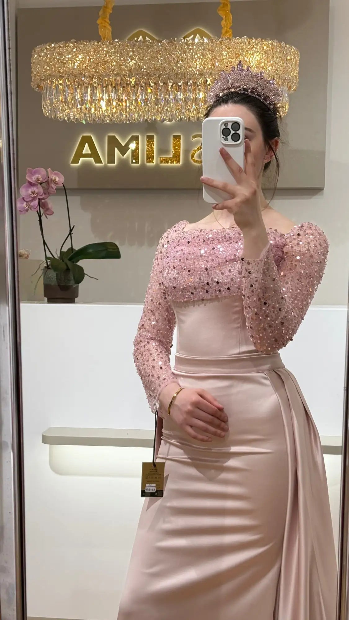 Ein zartrosa Satingown mit langen Ärmeln, verziert mit funkelnden Pailletten und einer taillierten Taille.